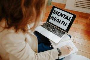 Image of person at computer that says mental health