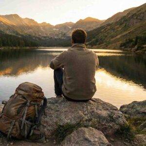 Person resting by a mountain lake, symbolizing peace from heavy stress and finding relief.