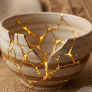 A ceramic bowl repaired with golden lacquer using the Kintsugi method, symbolizing how therapy can transform moral injury and brokenness into a source of strength and resilience.